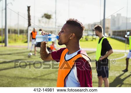 Stock Image - Soccer player drinking water on field. Fotosearch