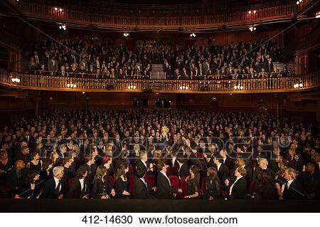 Stock Image - Spotlight on audience member clapping in theater. Fotosearch