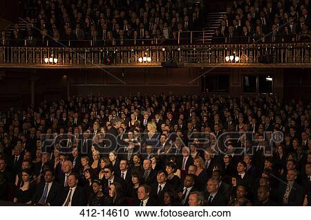 Stock Image - Spotlight on audience members handshaking in theater. Fotosearch