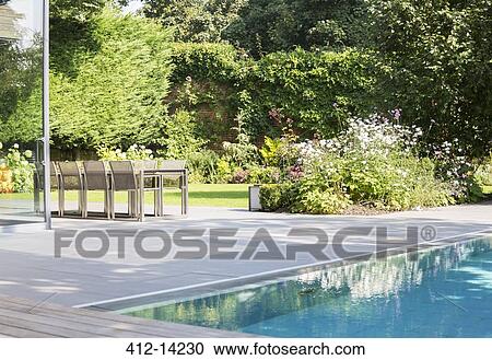 Table and chairs by outdoor swimming pool View Large Photo Image Stock Image - Table and chairs by outdoor swimming pool. Fotosearch
