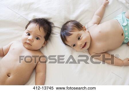 Stock Photography - Twin baby girls laying on bed. Fotosearch