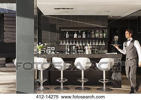 Waiter carrying tray of glasses in bar View Large Photo Image Stock Photography - Waiter carrying tray of glasses in bar. Fotosearch