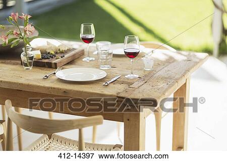 Stock Photo - Wine and appetizer on wooden dining table on patio. Fotosearch