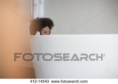 Woman listening to headphones in bath View Large Photo Image Stock Image - Woman listening to headphones in bath. Fotosearch