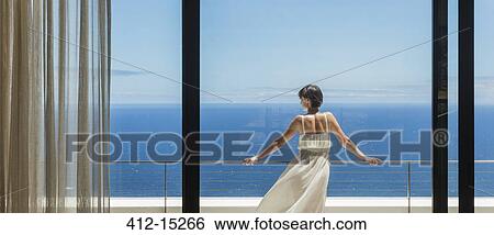 Stock Photograph - Woman looking at ocean from balcony. Fotosearch