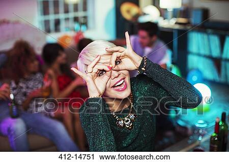 Stock Image - Woman making face in living room at party. Fotosearch
