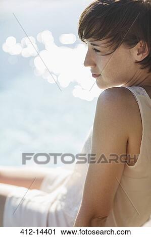Stock Image - Woman relaxing at poolside. Fotosearch