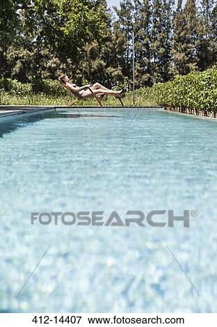 Woman relaxing by swimming pool View Large Photo Image Stock Photo - Woman relaxing by swimming pool. Fotosearch
