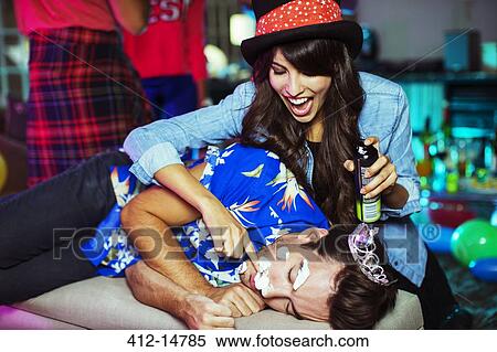 Woman spraying shaving cream on sleeping man's face at party View Large Photo Image Stock Photography - Woman spraying shaving cream on sleeping man's face at party. Fotosearch