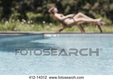 Stock Image - Woman sunbathing by swimming pool. Fotosearch