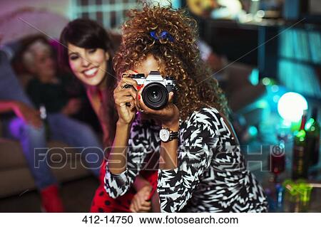 Woman using camera in living room at party View Large Photo Image Stock Image - Woman using camera in living room at party. Fotosearch