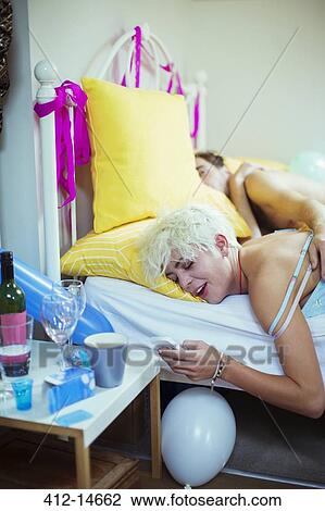 Woman using cell phone in bed the morning after a party View Large Photo Image Stock Image - Woman using cell phone in bed the morning after a party. Fotosearch