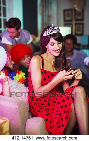 Woman using cell phone on sofa at party View Large Photo Image Stock Image - Woman using cell phone on sofa at party. Fotosearch