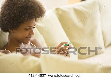 Woman using cell phone on sofa View Large Photo Image Stock Photo - Woman using cell phone on sofa. Fotosearch