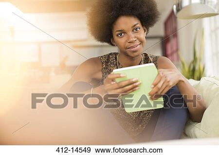 Stock Photo - Woman using digital tablet on sofa. Fotosearch