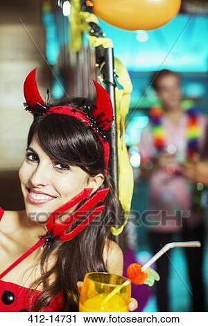Stock Image - Woman wearing devil costume at party. Fotosearch