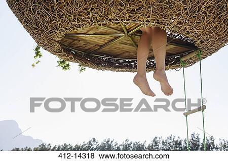 Stock Photo - Woman's feet dangling out of nest tree house. Fotosearch