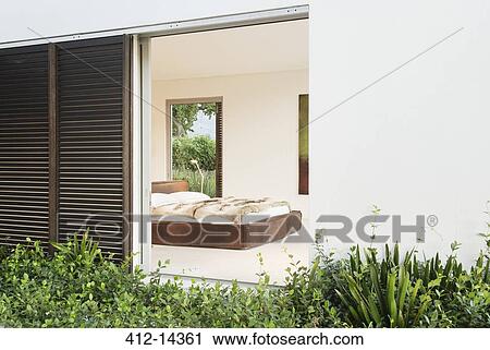 Stock Image - Wood shutters and sliding door to modern bedroom. Fotosearch