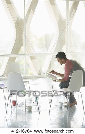 Businessman reviewing paperwork at circle of chairs View Large Photo Image Picture - Businessman reviewing paperwork at circle of chairs. Fotosearch