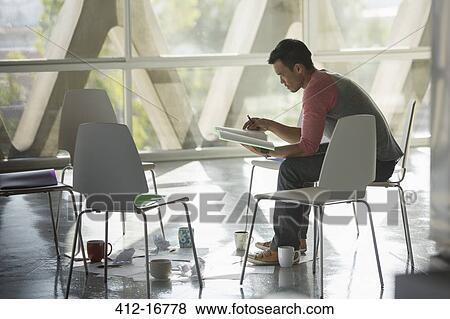 Businessman reviewing paperwork at circle of chairs View Large Photo Image Stock Photo - Businessman reviewing paperwork at circle of chairs. Fotosearch