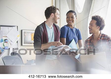 Stock Image - Casual business people discussing paperwork in meeting. Fotosearch