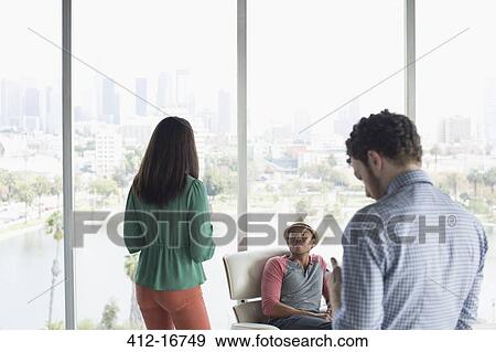 Casual business people in office overlooking city View Large Photo Image Stock Photo - Casual business people in office overlooking city. Fotosearch