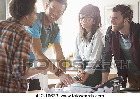 Stock Image - Casual business people talking in meeting at desk. Fotosearch