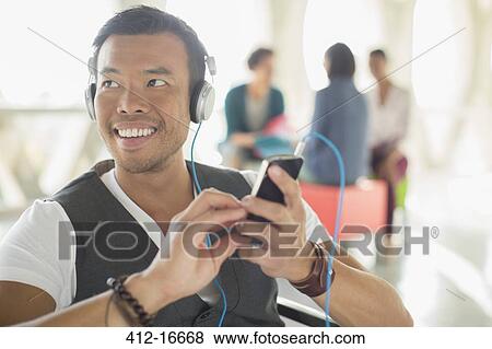 Casual businessman listening to music on headphones with mp3 player View Large Photo Image Stock Photo - Casual businessman listening to music on headphones with mp3 player. Fotosearch