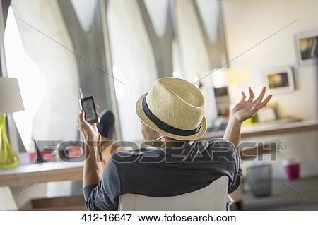 Stock Photo - Casual businessman talking on cell phone with feet up on desk. Fotosearch