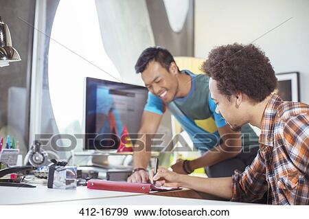 Stock Photo - Casual businessmen reviewing paperwork in office. Fotosearch