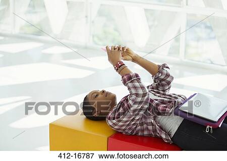 Casual businesswoman laying on bench and text messaging with cell phone View Large Photo Image Stock Photo - Casual businesswoman laying on bench and text messaging with cell phone. Fotosearch
