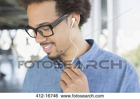 Stock Photograph - Close up of man in eyeglasses listening to music on headphones. Fotosearch