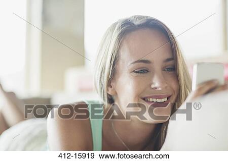 Stock Photo - Close up of smiling woman texting with cell phone. Fotosearch
