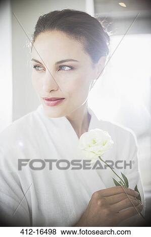 Stock Photo - Close up of woman in bathrobe holding white rose. Fotosearch