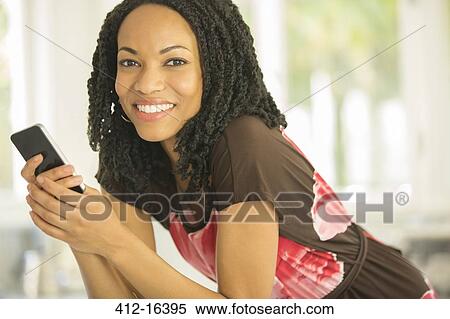 Stock Photography - Close up portrait of smiling woman holding cell phone. Fotosearch