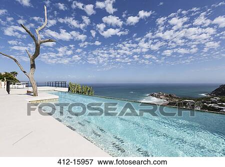 Clouds in blue sky over luxury lap pool overlooking ocean View Large Photo Image Stock Photo - Clouds in blue sky over luxury lap pool overlooking ocean. Fotosearch
