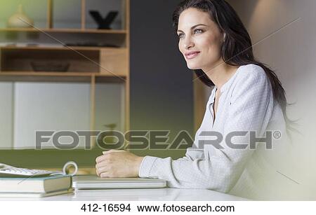 Confident woman sitting at table View Large Photo Image Picture - Confident woman sitting at table. Fotosearch