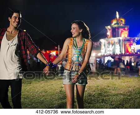 Couple holding hands and leaving music festival View Large Photo Image Stock Photograph - Couple holding hands and leaving music festival. Fotosearch