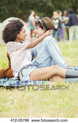 Stock Photograph - Couple hugging on blanket in grass at music festival. Fotosearch