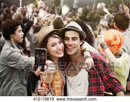 Stock Photo - Couple taking self-portrait at music festival. Fotosearch
