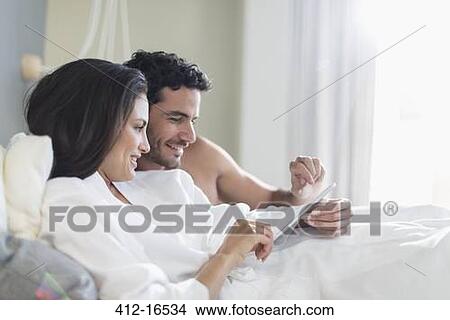 Couple using digital tablet in bed View Large Photo Image Picture - Couple using digital tablet in bed. Fotosearch