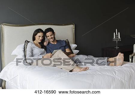 Stock Image - Couple using digital tablet in bedroom. Fotosearch