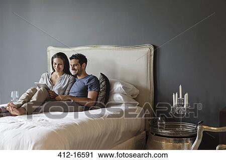 Couple using digital tablet in bedroom View Large Photo Image Stock Image - Couple using digital tablet in bedroom. Fotosearch