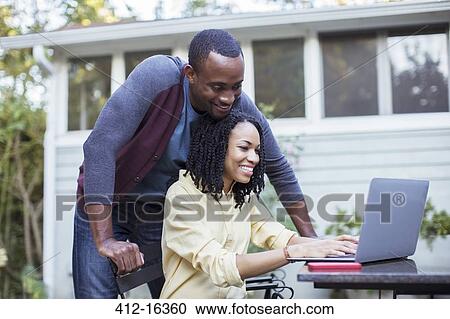 Couple using laptop at patio table View Large Photo Image Stock Image - Couple using laptop at patio table. Fotosearch