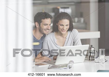 Couple using laptop at table View Large Photo Image Stock Image - Couple using laptop at table. Fotosearch