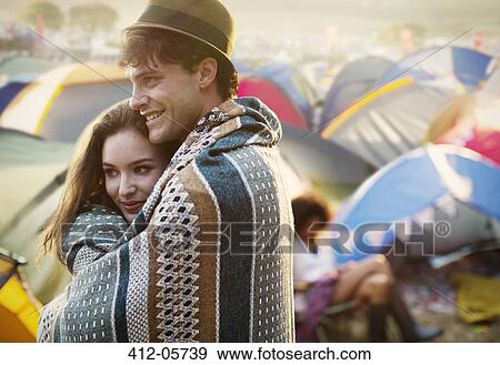 Couple wrapped in a blanket outside tents at music festival View Large Photo Image Stock Photo - Couple wrapped in a blanket outside tents at music festival. Fotosearch