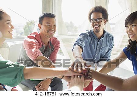 Stock Image - Creative business people connecting hands in huddle. Fotosearch