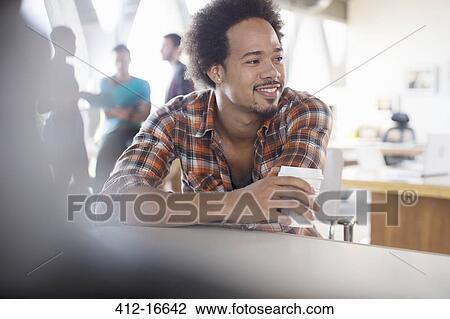 Stock Image - Creative businessman drinking coffee in office. Fotosearch
