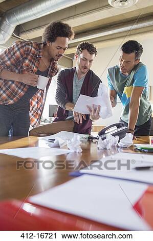 Creative businessmen reviewing paperwork in meeting at desk View Large Photo Image Stock Image - Creative businessmen reviewing paperwork in meeting at desk. Fotosearch