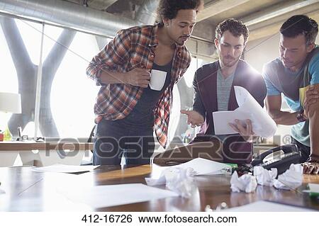 Creative businessmen reviewing paperwork in meeting View Large Photo Image Stock Photograph - Creative businessmen reviewing paperwork in meeting. Fotosearch